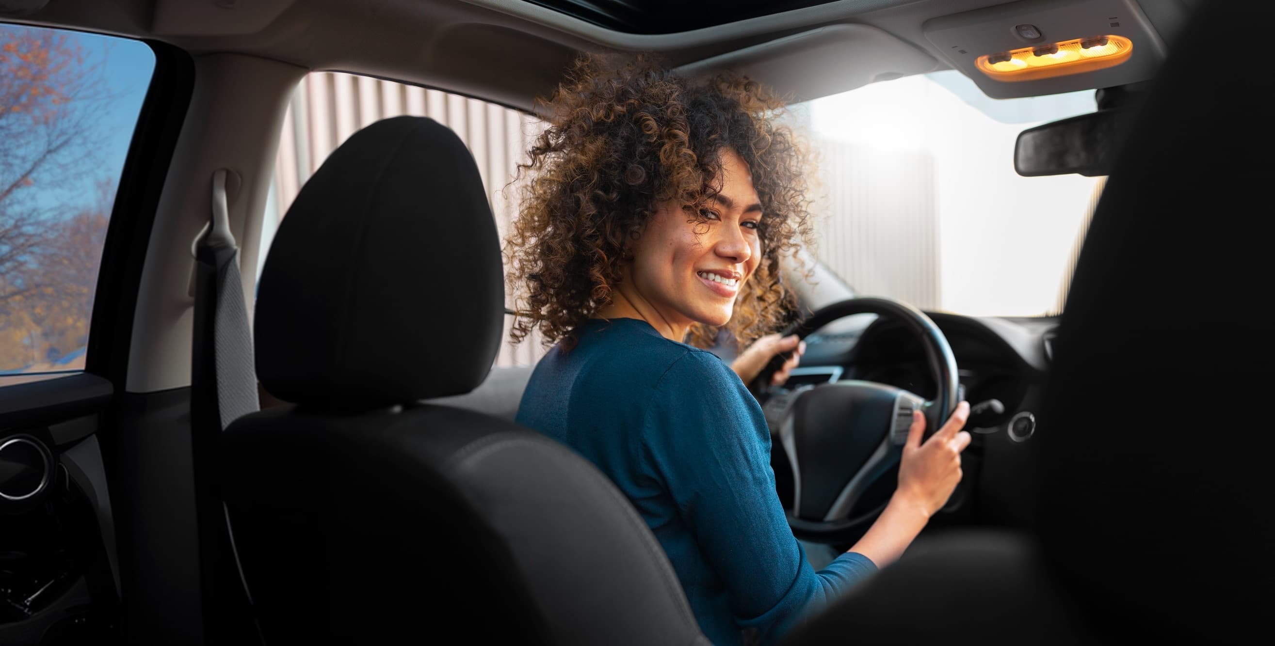Smiling rideshare driver looking back from the wheel